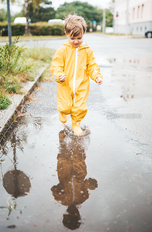 小男孩在雨中玩耍，跳进水里画画