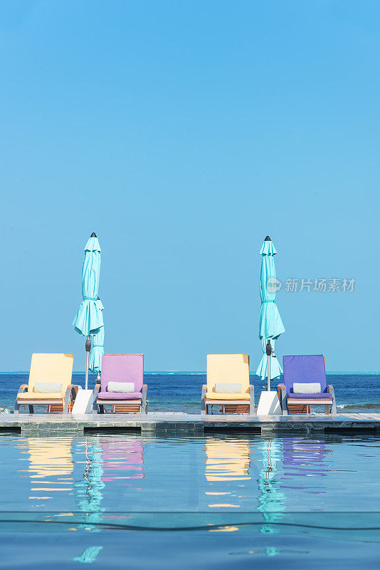 热带海滩度假村游泳池配有躺椅和雨伞
