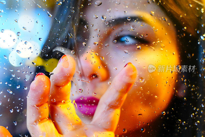 年轻女子的手在雨中的窗口忧郁而悲伤