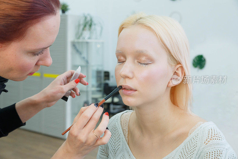 化妆的过程。化妆艺术家用画笔在模特脸上工作。