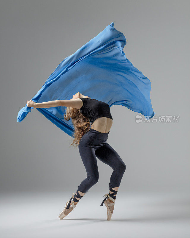 灰色背景下蓝色布料的芭蕾舞演员