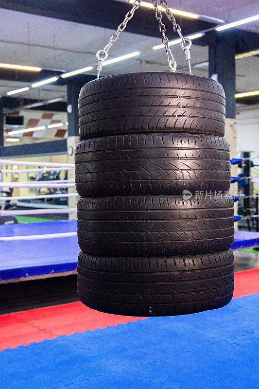 一堆用于拳击和踢腿的轮胎在拳击圈背景下的健身房