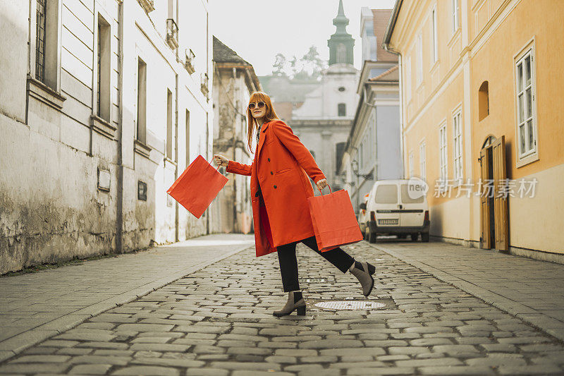 红发女孩在城里拎着购物袋