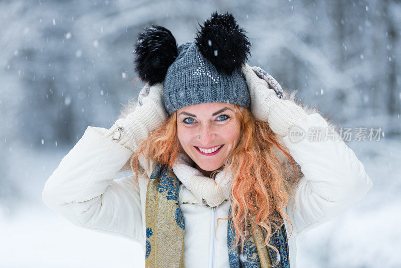 快乐的女人，在冬天森林附近的白雪皑皑的草地上