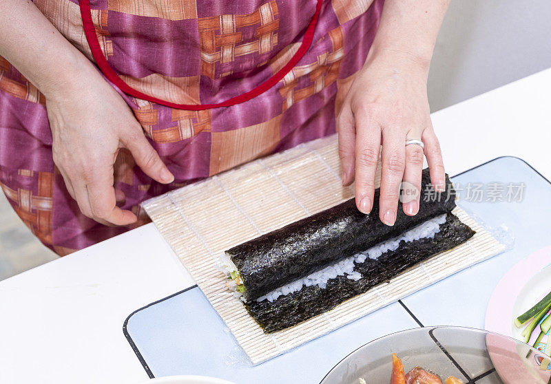 女孩的手正在准备寿司卷。日本料理在家。