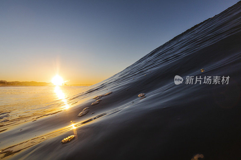 在温暖的日出海滩上形成平滑的波浪的特写