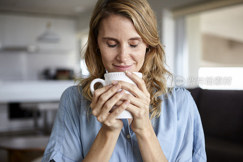 中年妇女举着一杯茶，闭着眼睛闻它的肖像