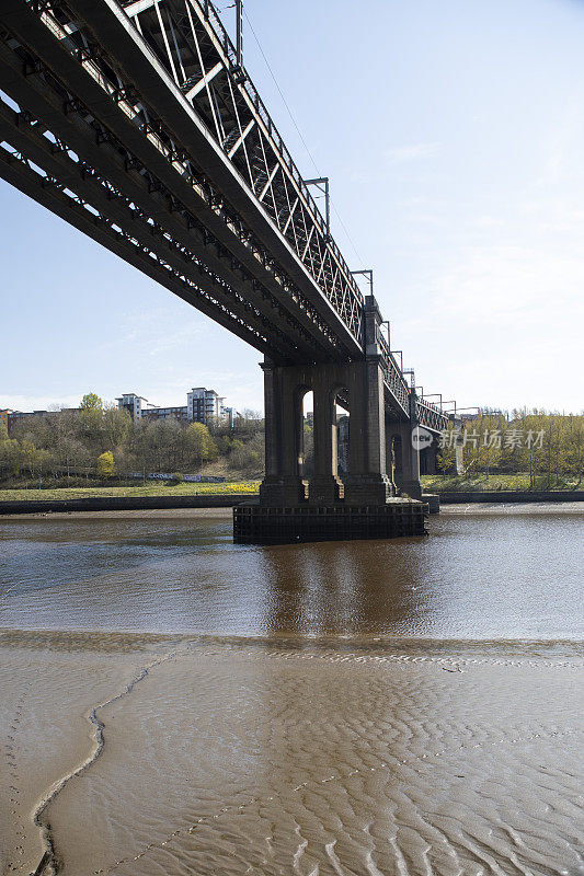 低潮时横跨河流的铁路桥，前景是暴露的泥浆