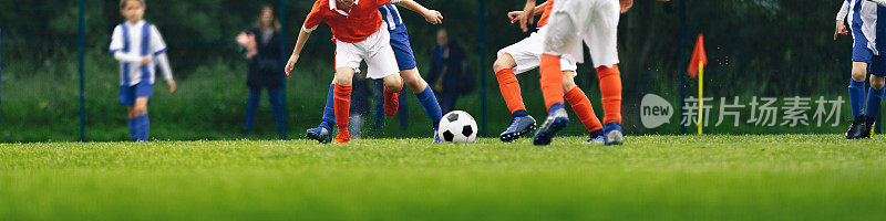 水平图像的青年足球比赛。孩子们在踢足球比赛。一群男生在天然草地上跑步踢球