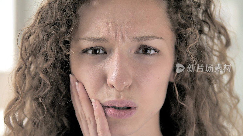 牙痛，卷发女人的脸靠近与牙痛