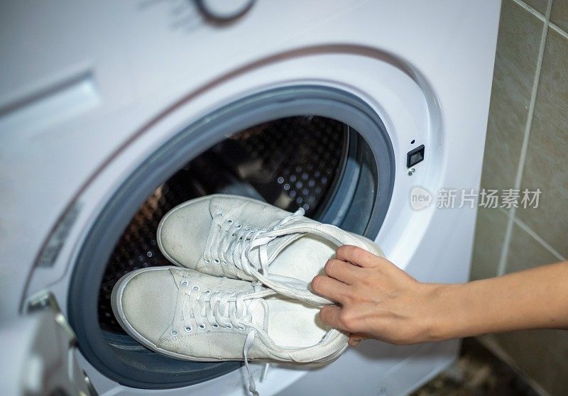 鞋类卫生。洗衣机里的一双脏白色运动鞋
