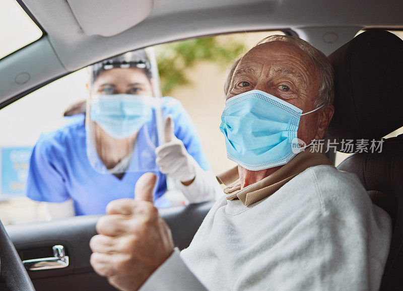 一名年长男子和一名年轻医护人员在穿过疫苗接种点的车道上竖起大拇指