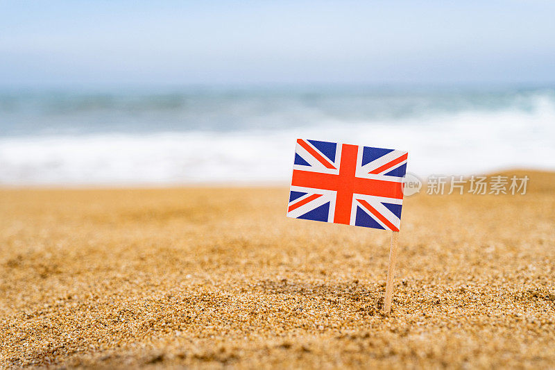 英国国旗以牙签的形式出现在沙滩对面的海浪中。旅游的概念