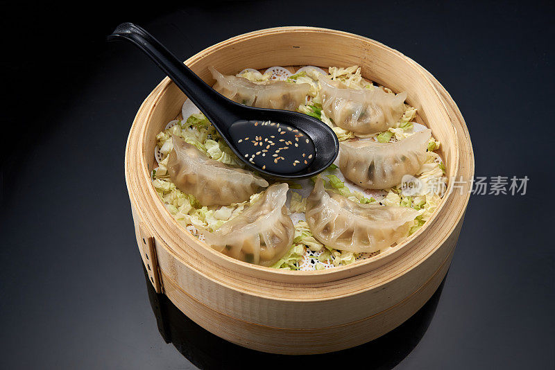 亚洲美食:用竹制的双层蒸锅煮豆腐包饺子，深色背景上淋着酱油