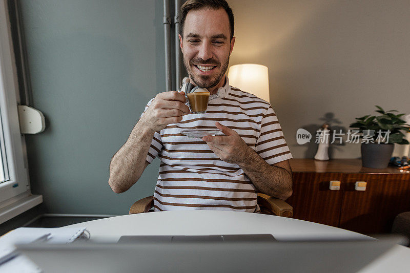 中年男子一边喝咖啡一边看笔记本电脑