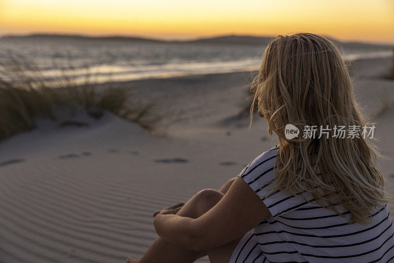 意大利撒丁岛，海滩上看日落的女人。