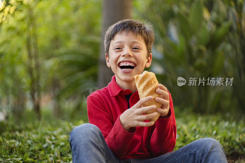 在绿色背景下吃面包的男孩