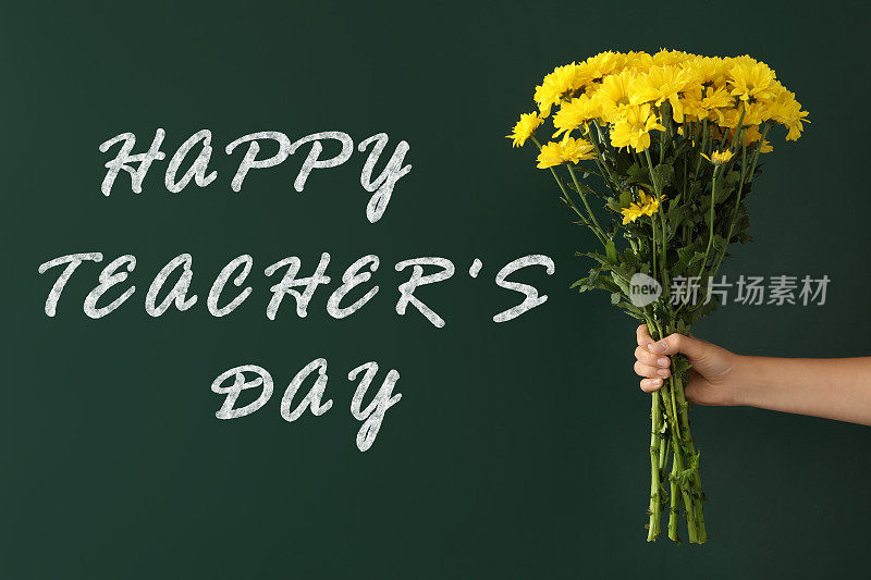 女孩捧着美丽的花束靠近绿色的黑板，上面写着:教师节快乐，特写