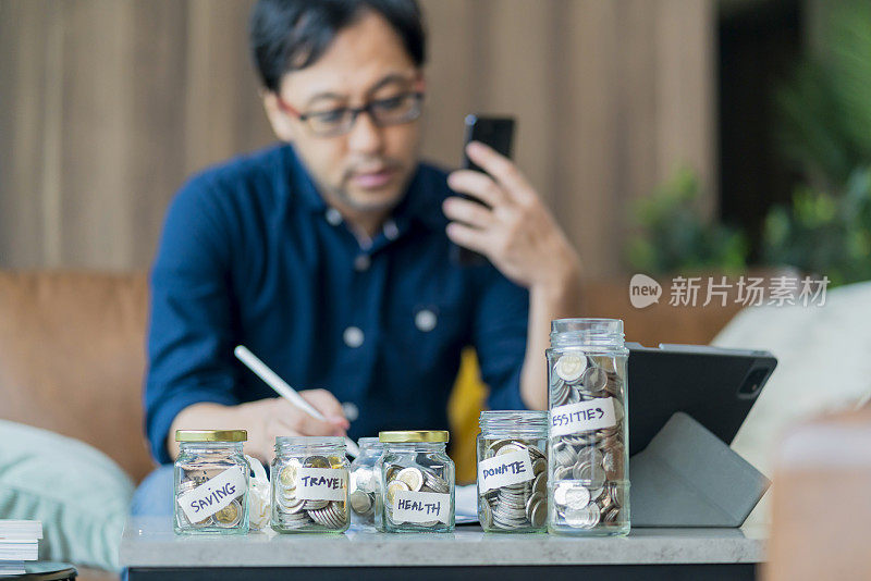 亚洲成年男子使用智能手机和账单，检查债务成本估算在家里的财务概念，开始计算财务，并咨询助理延长付款期限