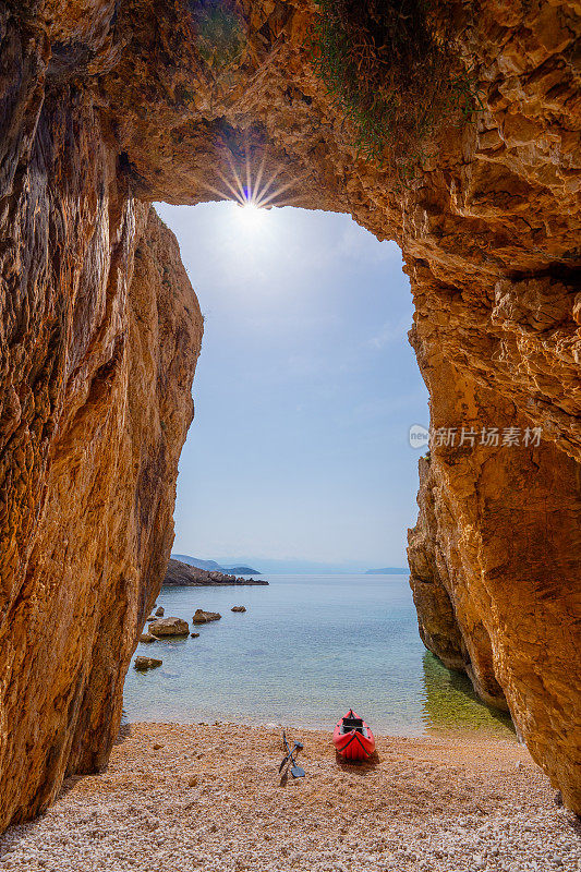 在悬崖和星星形状的太阳之间的小海滩上的海上皮艇