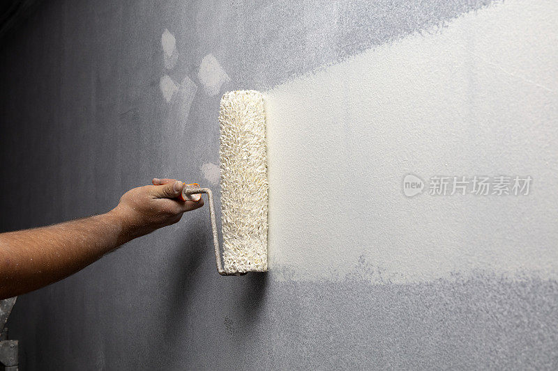 家庭油漆工正在用油漆滚筒刷墙