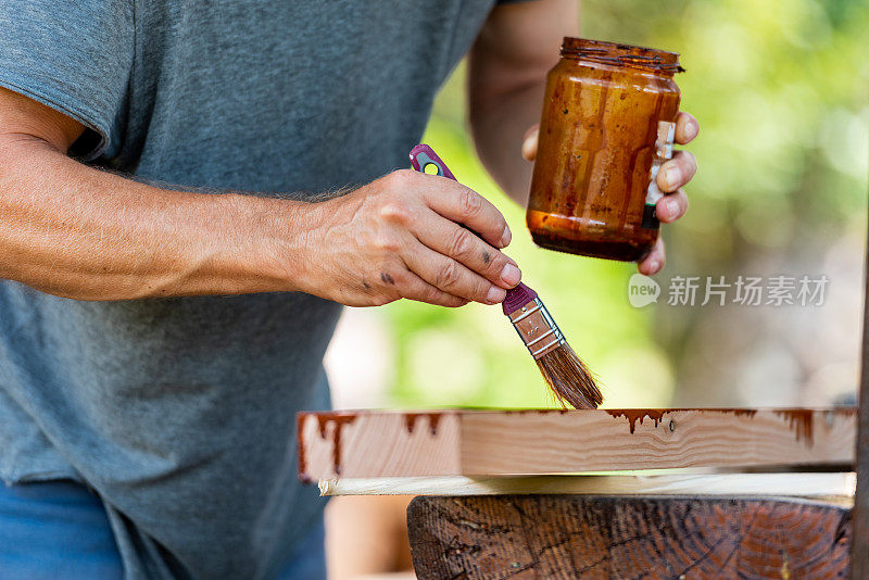 在阳光明媚的日子里，男人正在为家里的露台粉刷木板