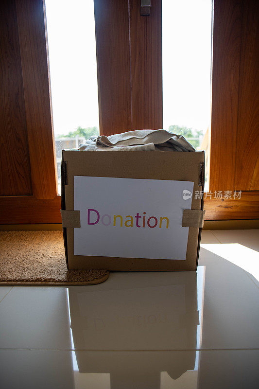 捐赠的概念。带有捐赠标签的布盒。家里的旧衣服。