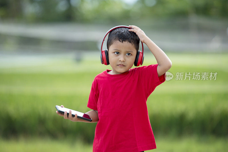 蹒跚学步的男孩用耳机听音乐