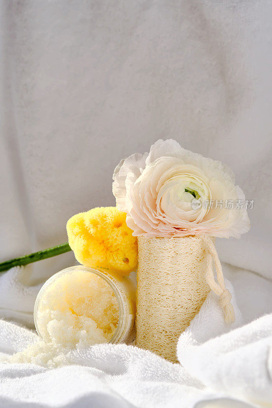 搓澡，丝瓜毛巾和有机海绵的背景上的毛巾形浴巾与鲜花。