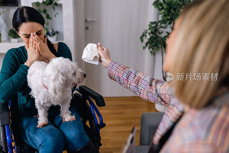 坐在轮椅上的年轻女子在她的治疗犬和心理治疗师面前找到了安慰和情感治疗