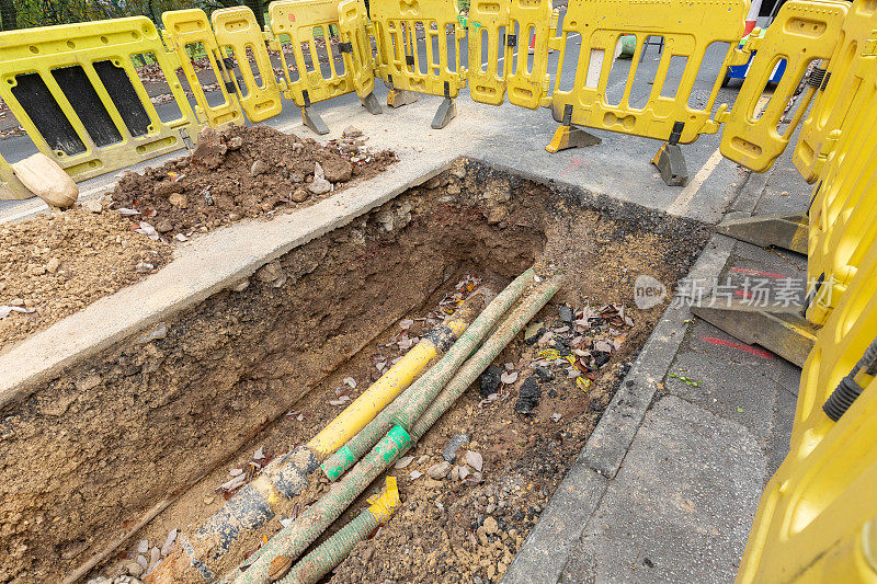 英国的道路工程正在挖掘当地的柏油路面，以修复地下的公用管道，并设置安全屏障和标志