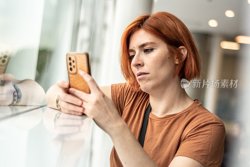 一名年轻女子在窗边使用手机