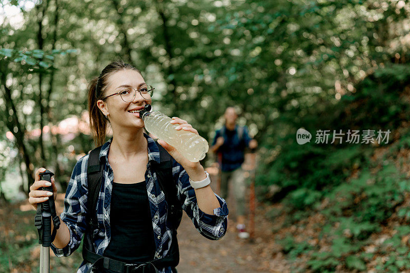 一名妇女在一次有益的徒步旅行中停下来喝水