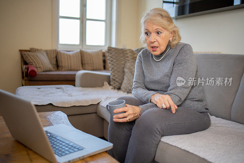 一位老妇人正在使用笔记本电脑