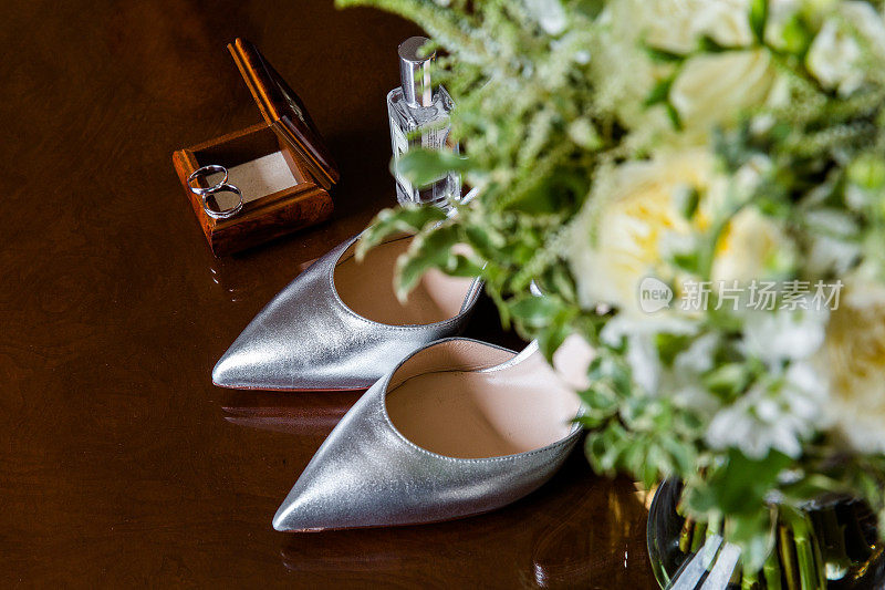 新娘的必需品有银鞋，木盒里的结婚戒指，香水和反光表面上的花束。忧郁地点燃一种亲密的感觉。