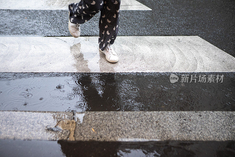 雨中走过斑马线的人