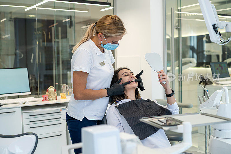 在牙科诊所里，年轻的女牙医正在给一个女病人做牙科检查。