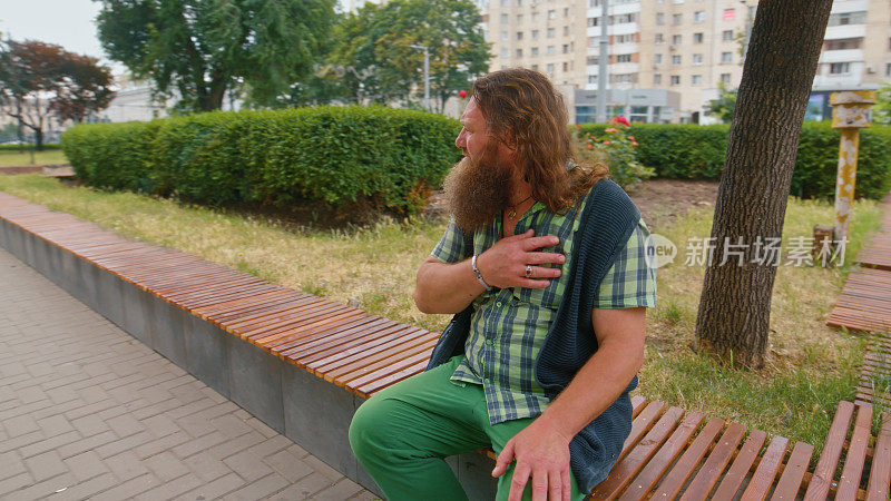 坐在公园里的长胡子红头发男子转身离开了镜头