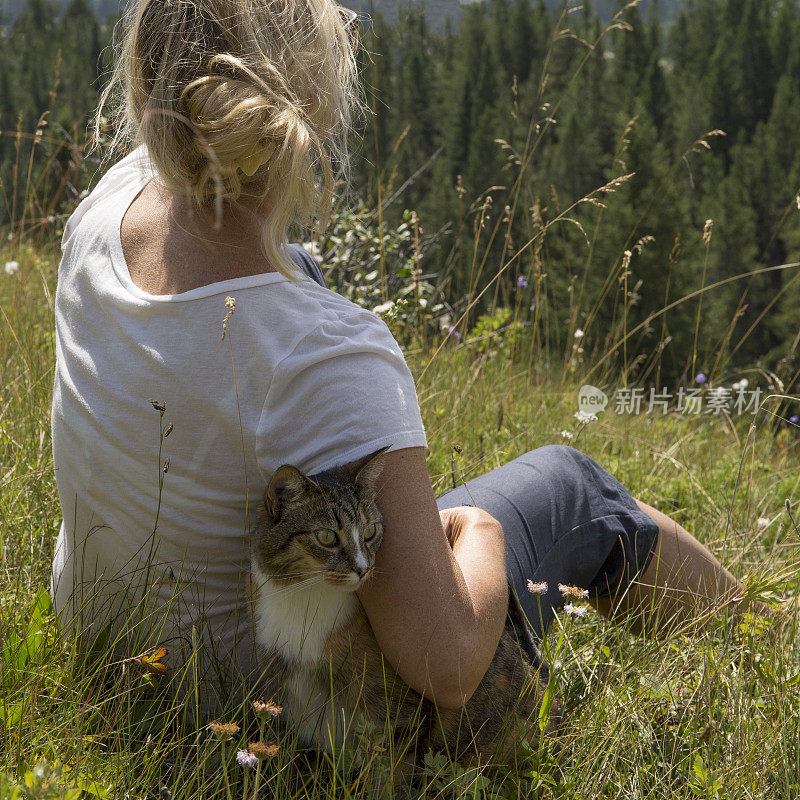 成熟的女人和猫在草地上放松