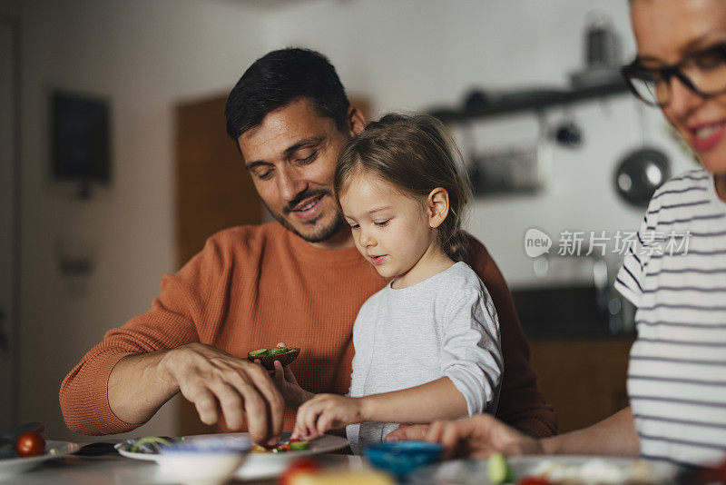 一个快乐的小女孩在家里和爸爸妈妈一起吃早餐的肖像