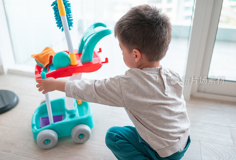 两岁半的小男孩开心地玩着他的清洁套装玩具和家务活动