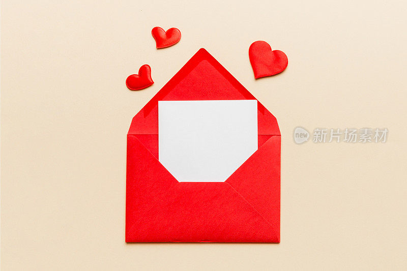 红纸信封，空白的白色卡片和彩色背景上的心。俯视图情人节概念