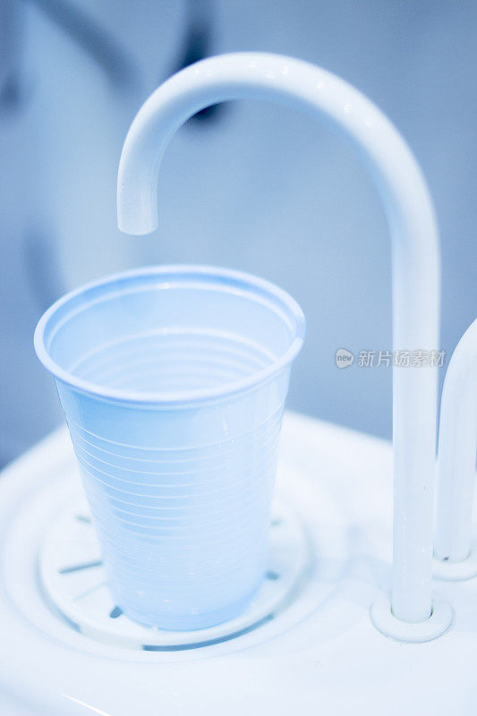 牙科医生在牙科诊所用清水冲洗杯子