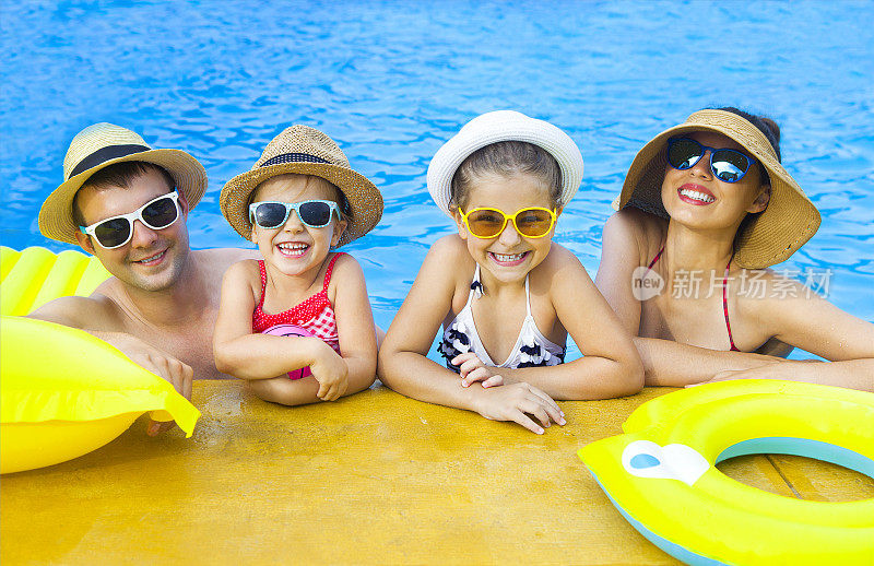 幸福的家庭和两个孩子在游泳池里玩