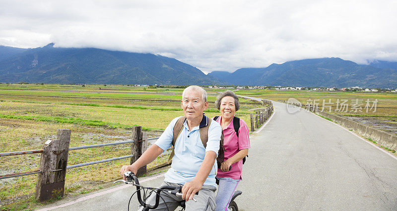 快乐的老夫妇在乡村公路上骑自行车