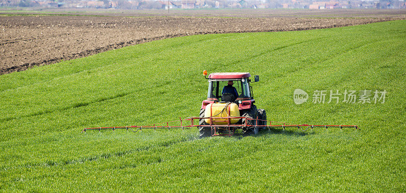 拖拉机用喷雾器向麦田喷洒除草剂和杀虫剂
