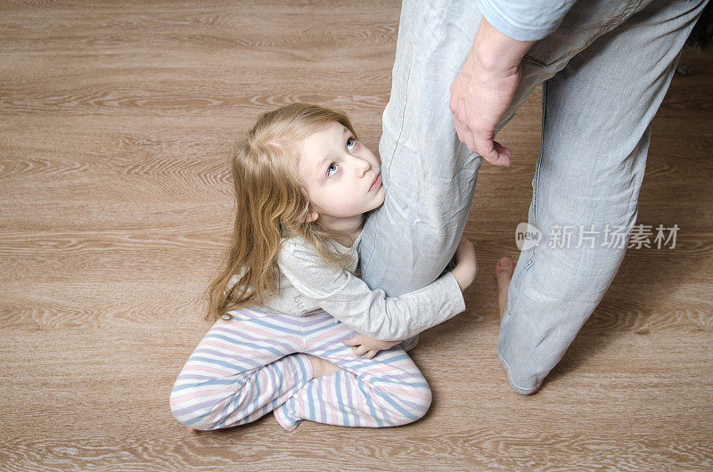 小女孩抱着她父亲的腿