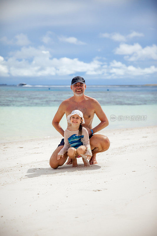 父亲和女儿蜷缩在海滩上的肖像