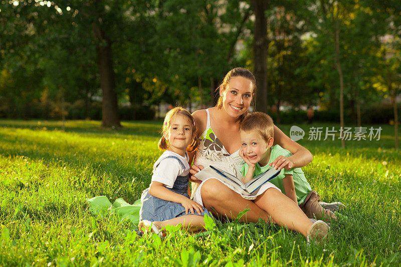 母亲带着女儿和儿子在户外看书