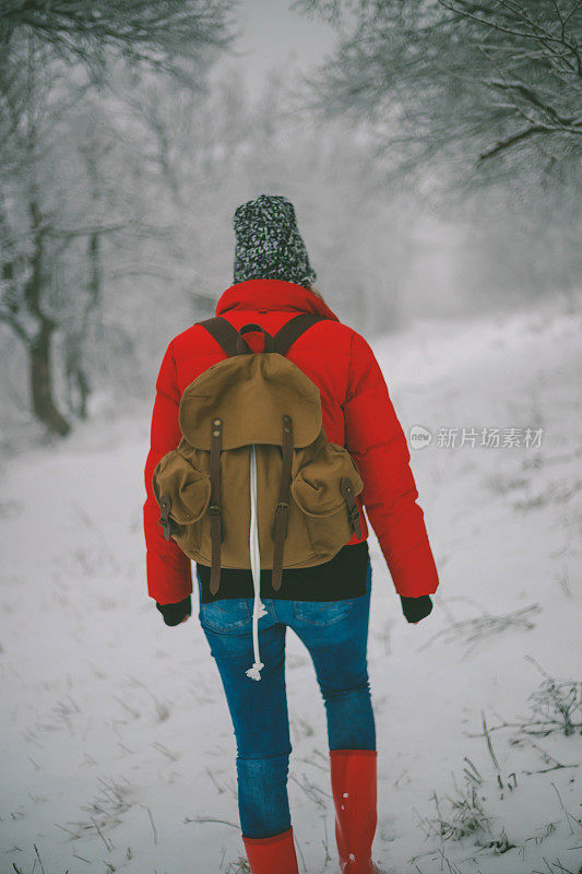 女徒步旅行者背包和雪鞋在雪地上的雪鞋